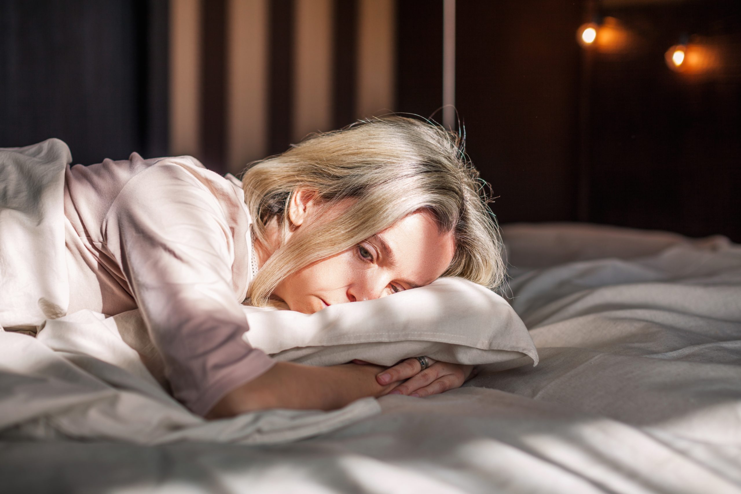 Bild zeigt Frau im Bett - es geht um psychische Belastungen durch chronischen dauerhaften Stress.